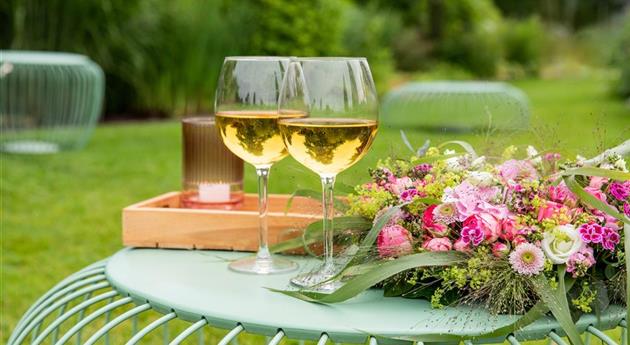 Blumenkranz und Weinschorle auf Gartentisch