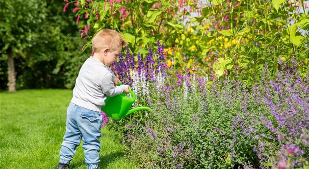Kind im Garten - Blumen gießen