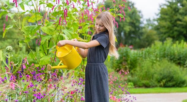Kind im Garten - Blumen gießen